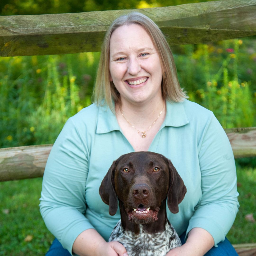 A woman relaxes on a bench with a dog